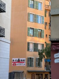 Façade ocre d'immeuble avec panneau de chantier AC BAT
